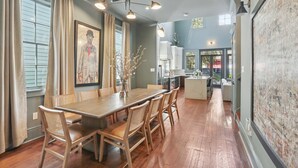 A dining area with a wooden table and chairs, a chandelier, and a large painting on the wall. - Designer Home on Magazine | Pool and Spa (New Orleans)