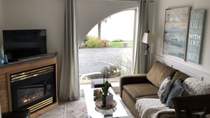 Un salon avec une cheminée, un canapé, une table basse et un téléviseur.