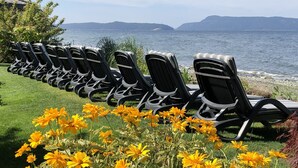 Une rangée de fauteuils noirs, disposés pour se détendre, avec vue sur la mer et les collines en arrière-plan.