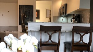 Une cuisine moderne avec un plan de travail blanc, des chaises en bois et une table basse en verre.