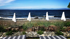 Un cadre idyllique au bord de la mer, avec une côte rocheuse, une rangée de parasols blancs et des chaises longues à rayures.