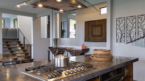 A modern kitchen with a gas stove, a kettle, and decorative bowls on the counter. - 6BR Luxury Contemporary Villa • Private Pool • Game Room • Quiet Setting (Manuel Antonio)