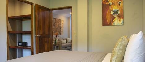Un dormitorio con una cama, un armario de madera, un cuadro de una vaca y un sofá al fondo.