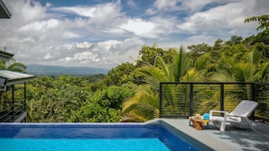 A pool with a view of lush greenery and mountains in the background. - 6BR Luxury Contemporary Villa • Private Pool • Game Room • Quiet Setting (Manuel Antonio)