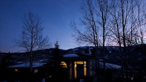 A cabin with a snow-covered roof, surrounded by trees and a mountainous backdrop. - Killer Views   -&-   Highest Reviews   -&-   Great Value  -&-  6 Min to Ski hill (Snowmass Village)