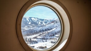 A round window with a view of snow-covered mountains and a valley. - Killer Views   -&-   Highest Reviews   -&-   Great Value  -&-  6 Min to Ski hill (Snowmass Village)