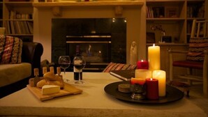 A cozy living room with a fireplace, bookshelves, and a table set with cheese, wine, and candles. - Killer Views   -&-   Highest Reviews   -&-   Great Value  -&-  6 Min to Ski hill (Snowmass Village)
