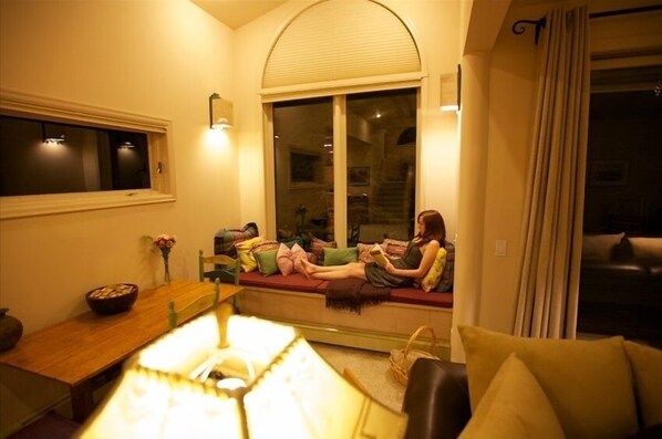 A cozy living room with a sofa, a table with a bowl, and a window with blinds.