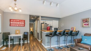 A modern kitchen with white cabinets, a stainless steel refrigerator, and a wooden island with bar stools. - GUEST HOUSE 1.5 miles to OU CAMPUS (Norman)