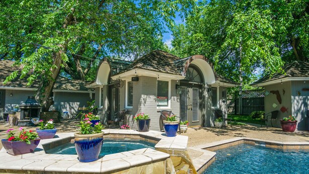 A pool area with a stone fountain, surrounded by potted plants and outdoor furniture. - GUEST HOUSE 1.5 miles to OU CAMPUS (Norman)