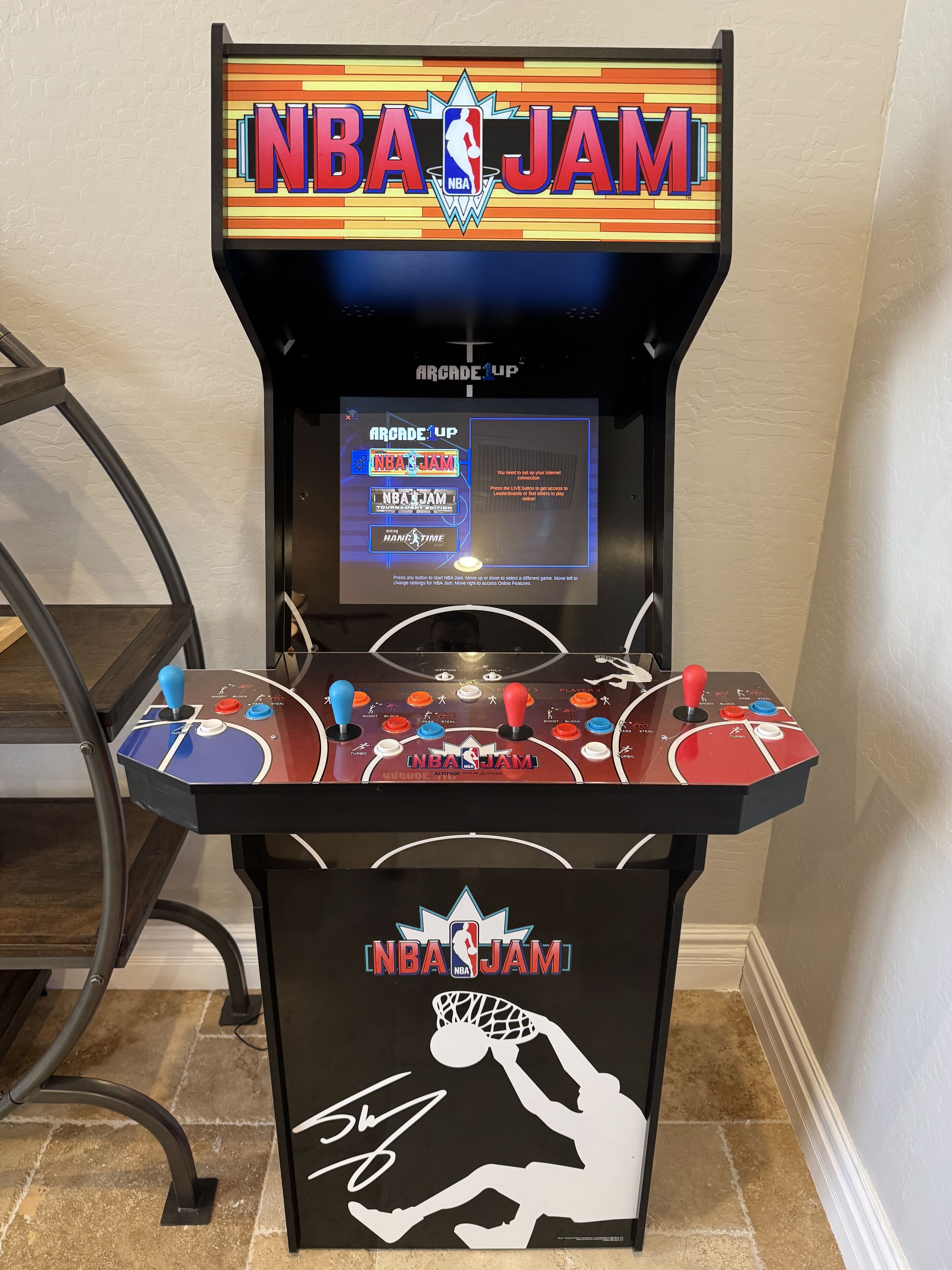 An NBA JAM arcade machine with a digital display and joystick controls.