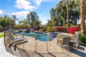 A backyard with a swimming pool, a hot tub, and a fenced deck area with lounge chairs. - Luxurious Family Rental w/ Heated Pool and sport court (Scottsdale)