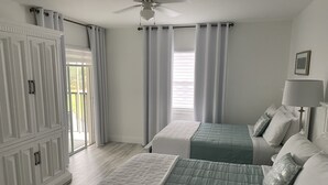 Une chambre avec deux lits, un ventilateur de plafond et une vue sur l’extérieur.