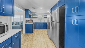 Una cocina compacta con armarios azules, un refrigerador de acero inoxidable y un microondas.