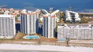 A coastal hotel complex with multiple high-rise buildings, a beach, and a swimming pool. - Beach Colony West 8E Beautiful Gulf Views from over sized balcony (Navarre)