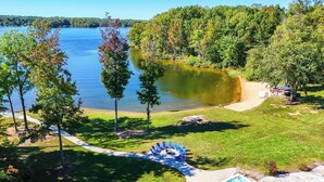 Una propiedad junto al lago con piscina, un patio con sillas y un sendero para caminar.