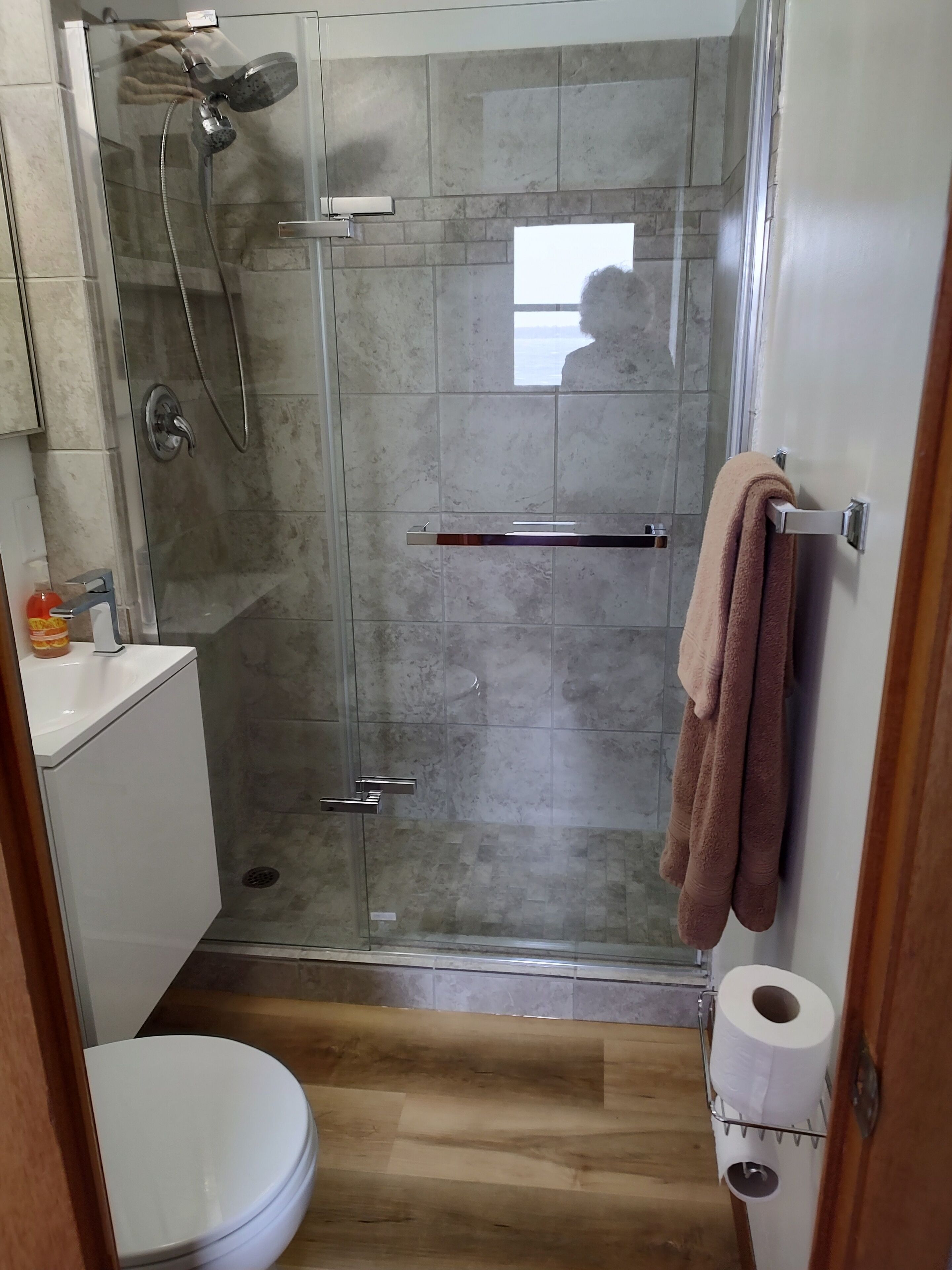 A bathroom with a glass-enclosed shower, a toilet, and a towel rack.