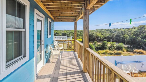 Une terrasse en bois offrant une vue sur une maison et la végétation environnante.