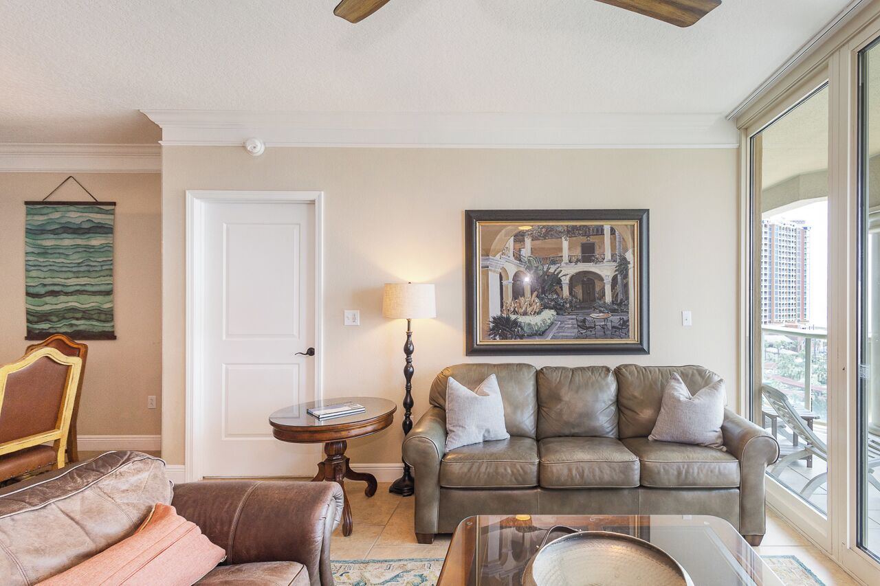 A living room with a brown leather sofa, a round side table, a lamp, and a framed picture on the wall.