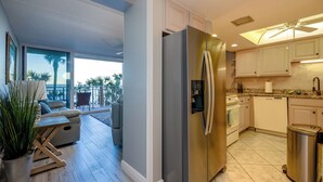 Una cocina moderna con refrigerador de acero inoxidable, gabinetes blancos y vistas al exterior.