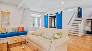 Un salon spacieux avec un canapé beige, une table basse en bois et un mur d’accent bleu.