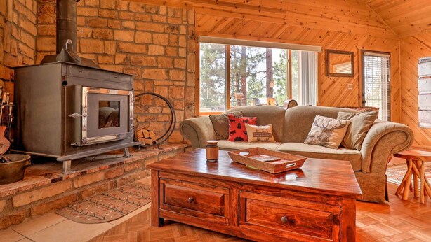 A cozy cabin interior with a wood-burning stove, a sofa, and a coffee table.