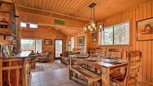 A wooden interior with a dining table set for four, a sofa, and a kitchen area with a wooden countertop.