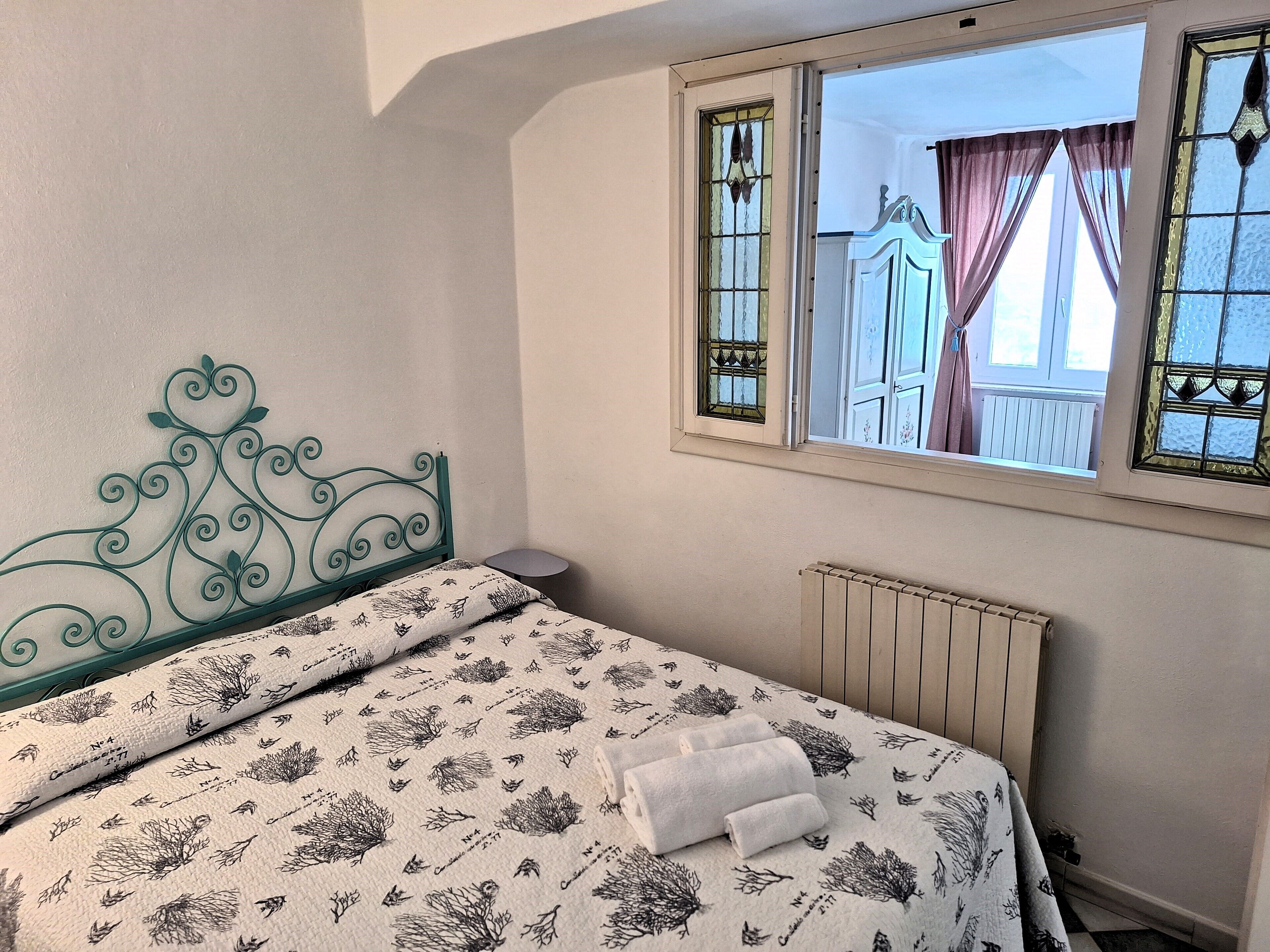 Une chambre à coucher avec un lit, un radiateur et une fenêtre avec des rideaux.