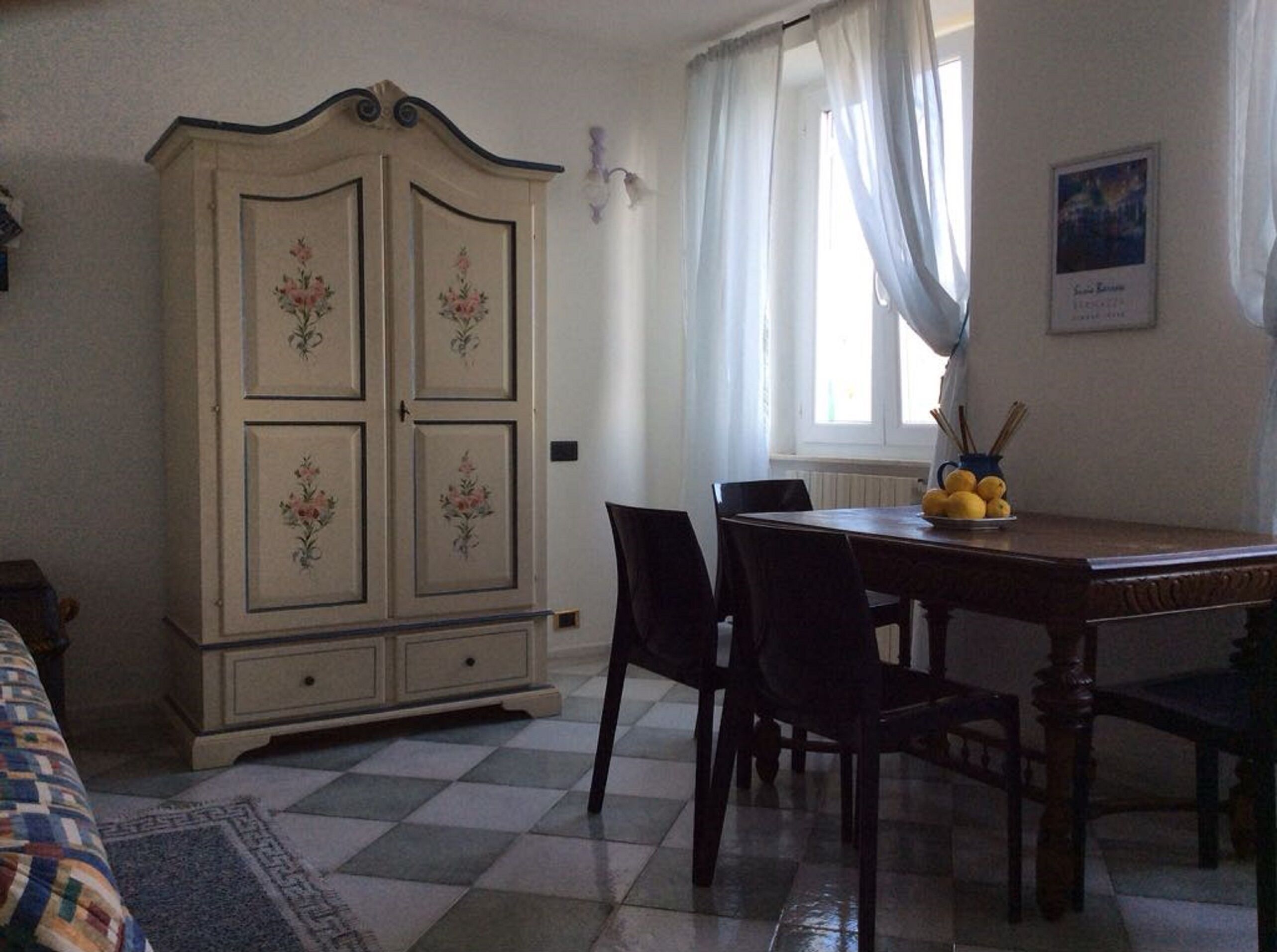 Un coin repas comprenant une table en bois, des chaises, un buffet orné de motifs floraux et une fenêtre avec des rideaux.
