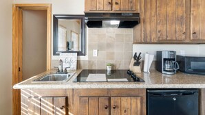 A kitchen with wooden cabinets, a stainless steel sink, a microwave, and a coffee maker. - Shoreside at CrossTimbers Marina (Sperry)
