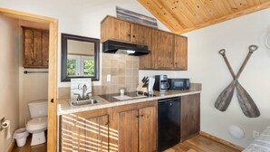 A compact kitchen with wooden cabinets, a dishwasher, a microwave, and a sink. - Shoreside at CrossTimbers Marina (Sperry)