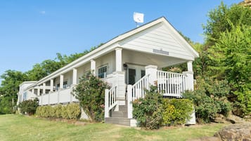 A white building with a covered porch and a flag on top.