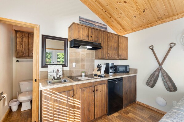 A compact kitchen with wooden cabinets, a dishwasher, a microwave, and a sink.