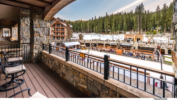 A wooden deck with stone walls, overlooking a ski resort with buildings and trees. - Luxury 3BD Village at Northstar Residence - Great Bear Lodge 303 (Truckee)