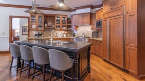 A spacious kitchen with wooden cabinets, a large island with bar stools, a microwave, and a stove. - Luxury 3BD Village at Northstar Residence - Great Bear Lodge 303 (Truckee)