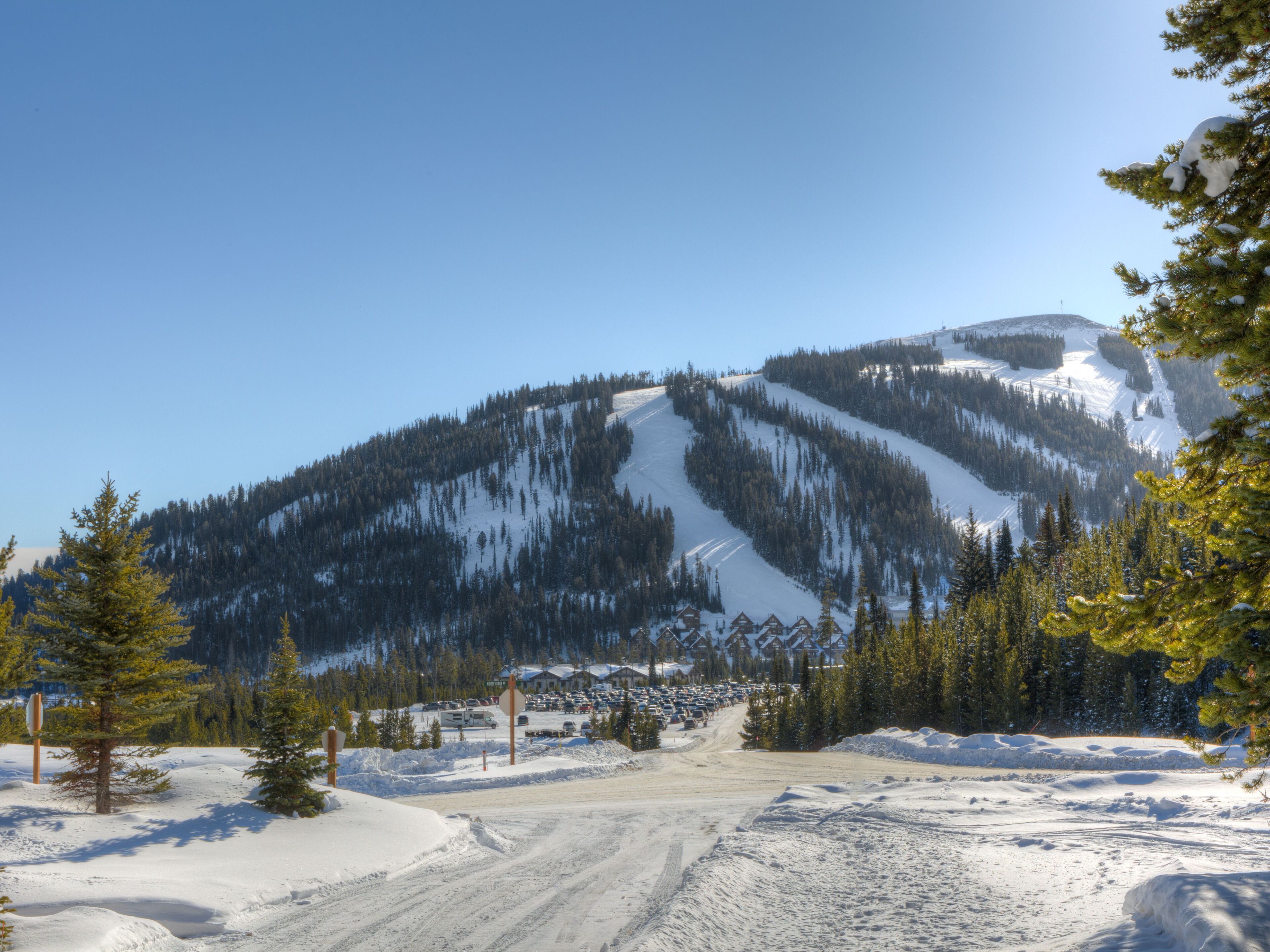 Une montagne enneigée, avec une station de ski en arrière-plan.