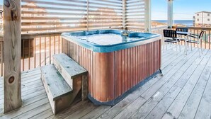 A wooden deck with a hot tub, wooden benches, and outdoor seating. - Oceanview Dog Friendly Home w/ Private Pool, Hot Tub, and Beach Access Nearby (Rodanthe)