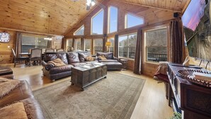 A spacious living room with a high ceiling, large windows, and a cozy fireplace. - "Blue Water Lodge" Jump'n Bridge, billiards, hot tub, dock, community pool (LaFollette)