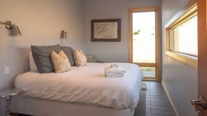 Un lit bien fait, avec une serviette pliée, une œuvre d’art encadrée accrochée au mur et une fenêtre donnant sur l’extérieur.