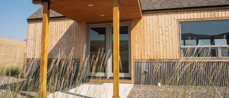 Un bâtiment en bois doté d’une entrée abritée et de grandes fenêtres.