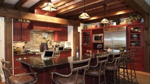 Un'ampia cucina con una grande isola, sgabelli da bar in legno ed elettrodomestici moderni.