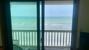 A view from a balcony overlooking a beach with a railing and a chair. - Beautiful Oceanfront Condo On 4th Floor - Steps From The Beach. Linens Incl. !!! (Surfside Beach)