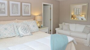 A bedroom with a bed, a nightstand, a lamp, a white sofa, and framed botanical prints on the wall. - Amazing Views at Dragonfly! HOT TUB! Kayaks, BOUNCER w Slide, SUP's, Fire Pit!  (Bracey)
