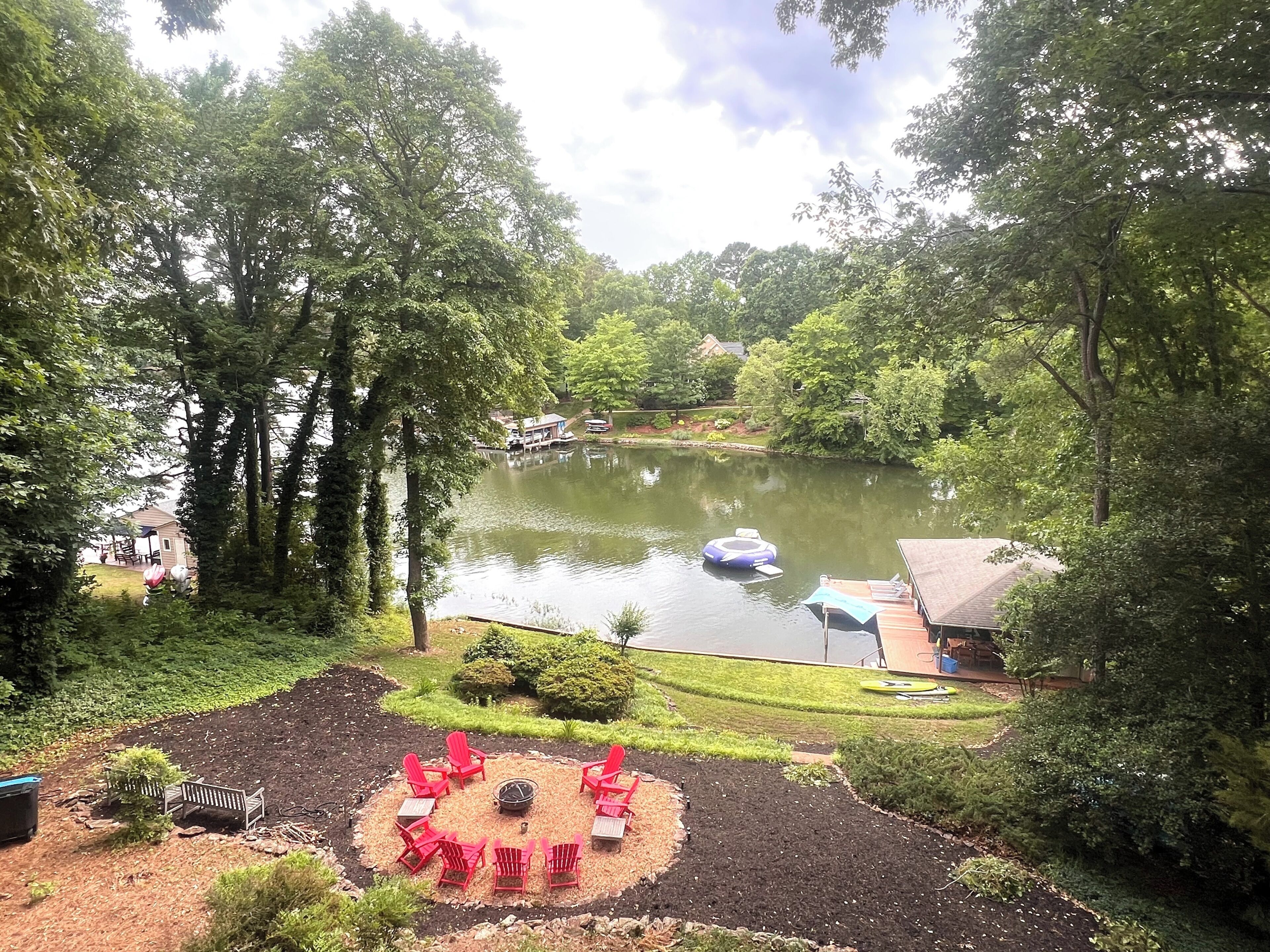 A lakeside property with a dock, outdoor seating area, and a small building.