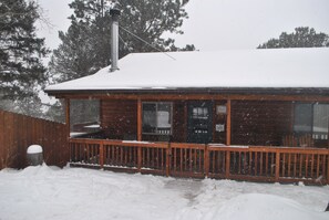 A wooden cabin with a covered porch and a snow-covered roof.