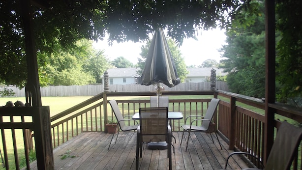 A wooden deck with a table and chairs, a covered area with an umbrella, and a view of a backyard. - Beach House in Rehoboth Beach, DE (Rehoboth Beach)