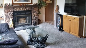 A living room with a fireplace, a sofa, a glass coffee table, a television, and a bookshelf. - Beach House in Rehoboth Beach, DE (Rehoboth Beach)