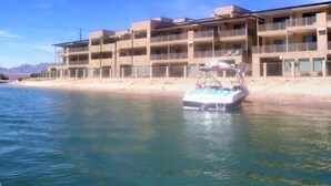 Un hotel de varios pisos con balcones, situado cerca de una masa de agua.