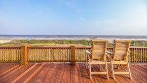 A wooden deck with two wooden chairs facing a beach view. - Beach Front Home, Huge Deck, Sleeps 12 (Crystal Beach)