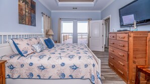 A bedroom with a bed, a dresser, a television, and a view to the outside. - Beach Front Home, Huge Deck, Sleeps 12 (Crystal Beach)